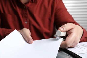 Man with papers using stapler at table, closeup