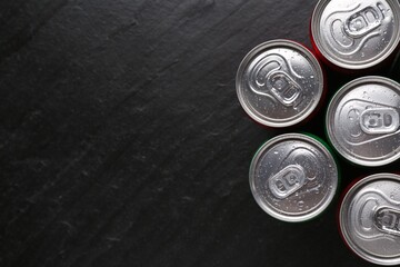 Energy drink in wet cans on black textured background, top view. Space for text