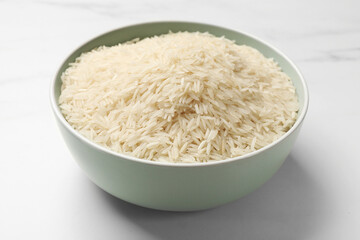 Raw basmati rice in bowl on white marble table