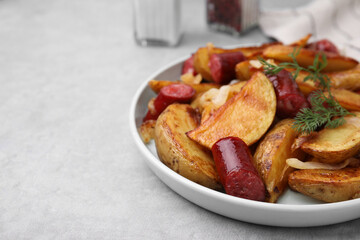 Delicious baked potato with thin dry smoked sausages, onion and dill on gray table, closeup. Space for text