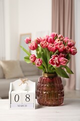 International Women's day - 8th of March. Block calendar and bouquet of beautiful tulips on white wooden table