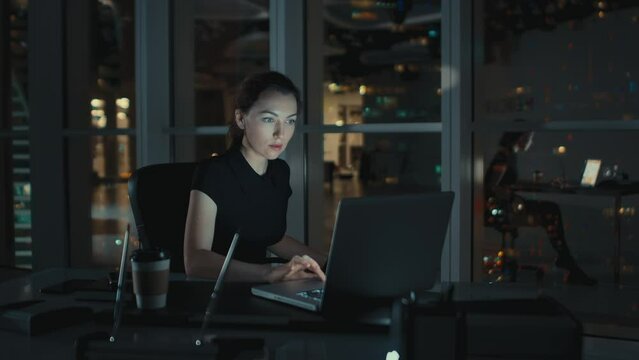 Business Woman in a Black Dress Sits at an Office Desk