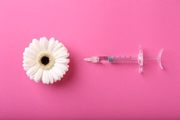 Cosmetology. Medical syringe and gerbera flower on pink background, flat lay