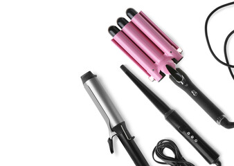 Different hair curling irons on white background, top view