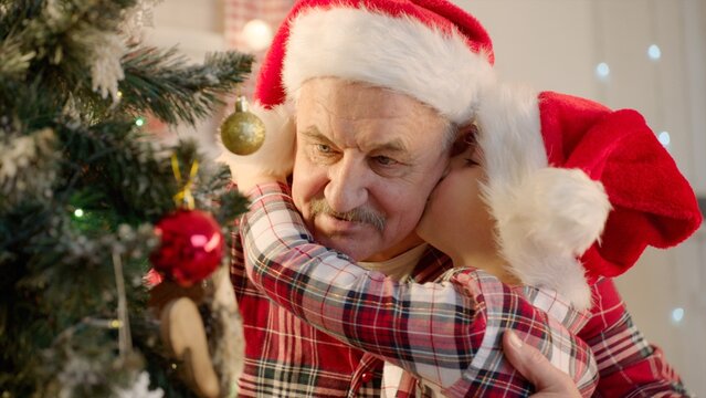 Senior man and his grandson decorating Christmas tree at home