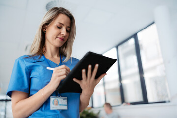 Portrait of confident female doctor standing in Hospital corridor. Beautiful nurse wearing blue...