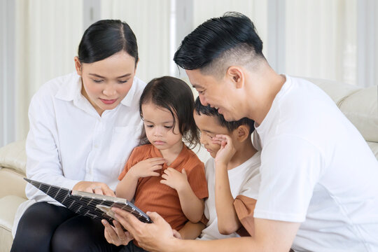Happy Asian family looking at a photo album at home