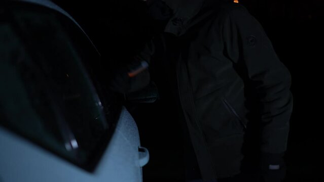 Man with hoodie tries to break car window at night