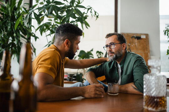 Best friends, supporting each other, drinking whiskey and talking. Discussing problems and drowning sorrows in alcohol. Concept of male friendship, bromance.