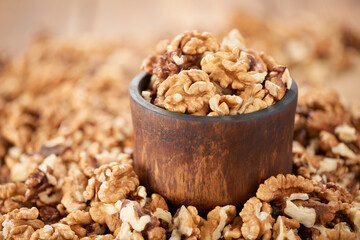 A bowl and a pile of peeled walnut kernels. Close-up. Low angle view.