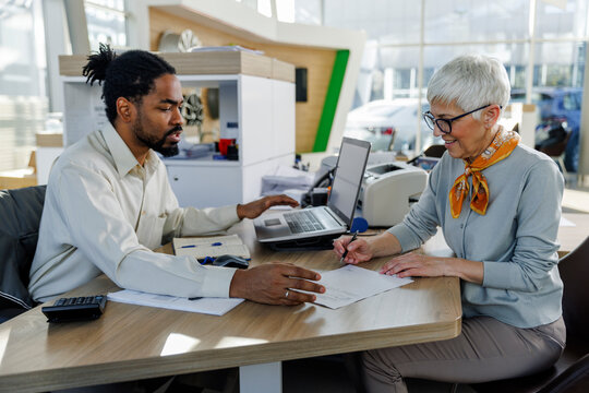 Salesperson with smiling customer doing paperwork at desk