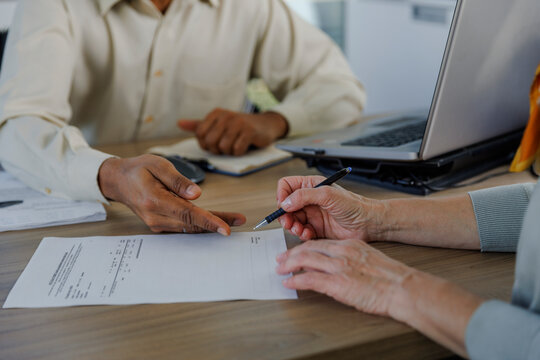 Salesperson with customer doing paperwork at desk