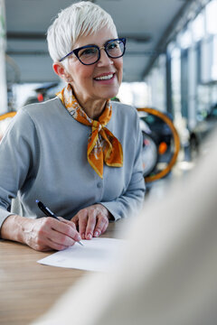 Happy senior woman doing paperwork at desk