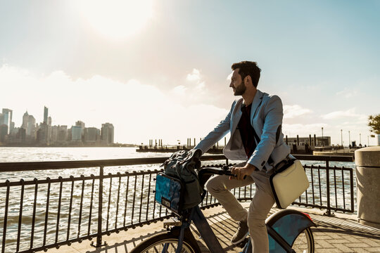 Businessman cycling on promenade in city