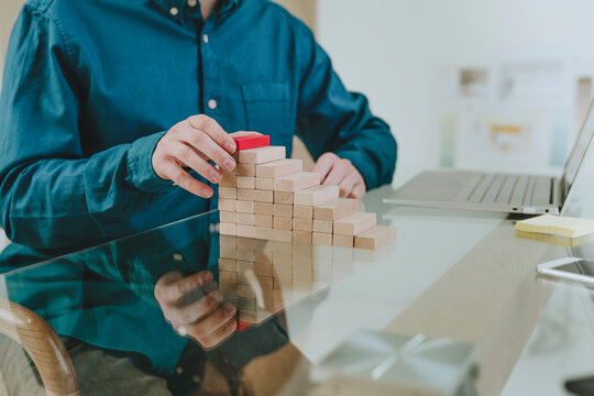 Businessman building steps using blocks at desk in office