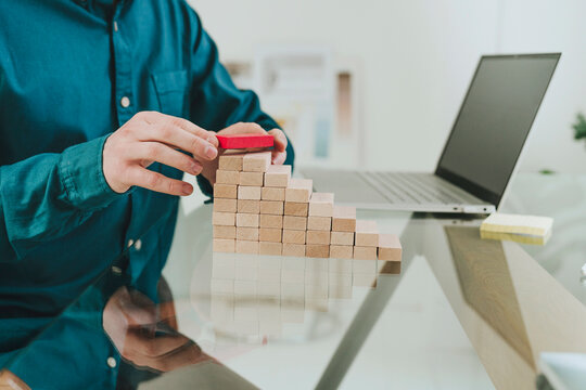 Businessman building steps using wooden blocks at desk in office