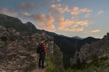 Fototapeta na wymiar Male traveler landscape photographer with a briefcase behind his back in the Polish Tatras at sunset.