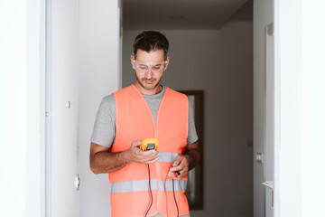Electrician holding voltage measuring equipment at home