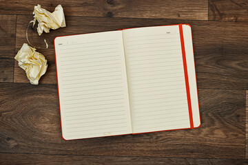 Blank page notebook or agenda with crumbled paper on wood table