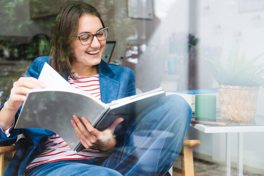 Happy freelancer examining reports sitting on chair at home office