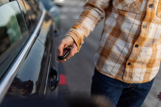 Man unlocking car with key on road