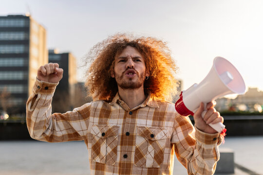 Angry man shouting with megaphone under sky