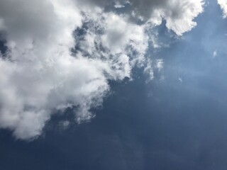 worm eye view shot of fluffy white clouds in the blue sky with bright sunlight at the right side of the frame