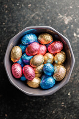 Easter chocolate eggs wrapped in aluminium foil in bowl. Top view.