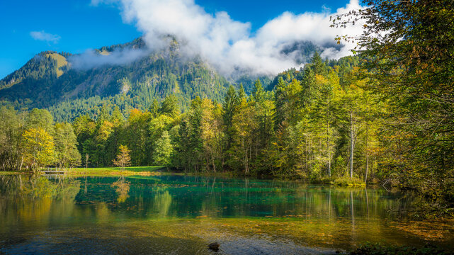 Germany, Bavaria, Oberstdorf, Scenic view of Christlessee lake with forested mountain in background