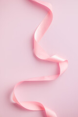 Curled pink ribbon on pink background.