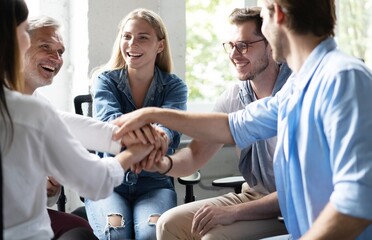 Happy businesspeople putting their hands on top of each other and laughing