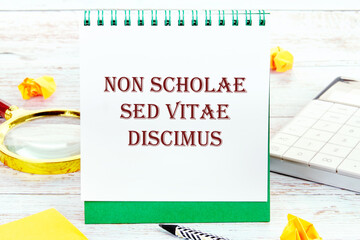 Non scholae sed vitae discimus It is translated from Latin as We study not for school, but for life. It is written on a standing notebook - obrazy, fototapety, plakaty
