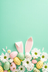 Easter crafting idea: Overhead vertical shot of vibrant eggs, cute bunny ears, and fresh daisy...
