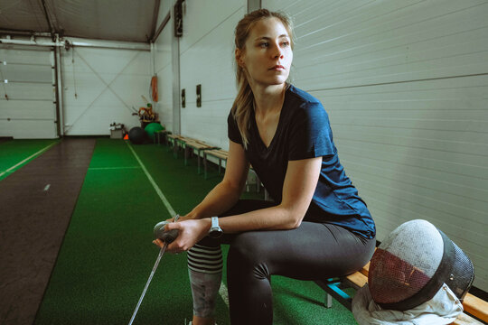 Woman in active wear sitting on bench in gym