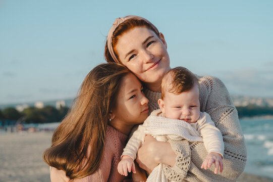 Smiling mother spending leisure time with daughters at beach on sunny day