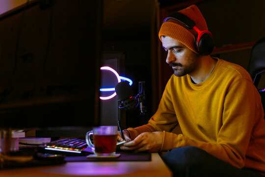 Writer wearing wireless headphones and writing on note pad at desk