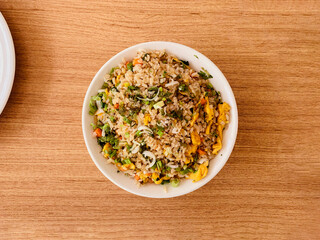 Top view of egg fried rice in a bowl on a brown wooden table