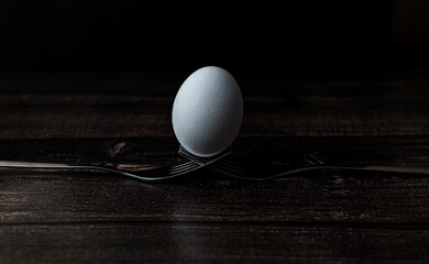 white egg lies on crossed rolls on a wooden background