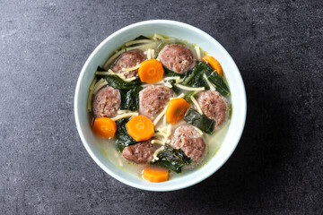 Italian Wedding Soup with meatballs and spinach on black background