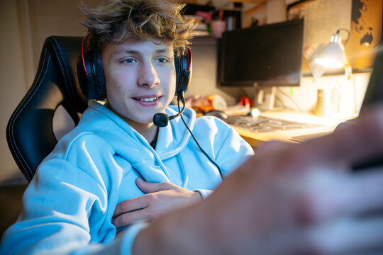 Smiling boy wearing headset and taking selfie at home