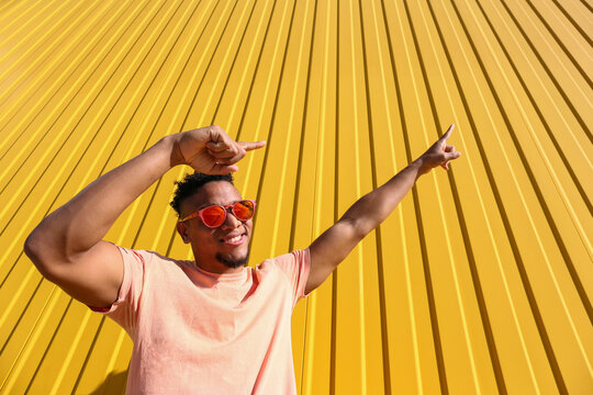 Happy young man dabbing in front of yellow wall