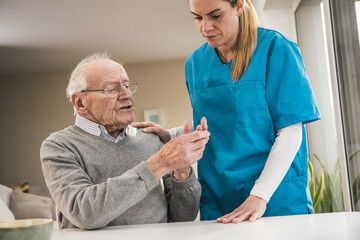 Senior man discussing with home caregiver at table