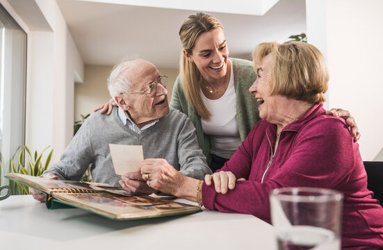Happy home caregiver with senior couple holding photograph