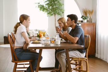 Happy Caucasian family talking and enjoying in a breakfast together at cozy home. Family enjoy meal