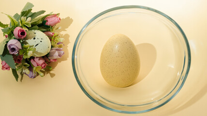 Creative Easter bouquet made of roses and Easter egg and one Easter egg in glass on pastel background.