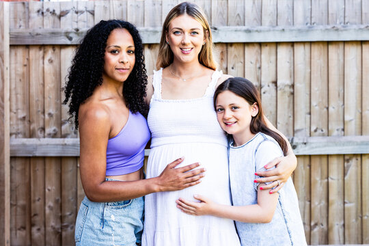 Smiling pregnant woman standing with family near fence