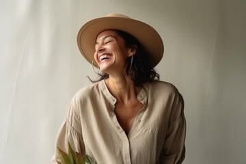 Beautiful young woman in hat and shirt smiling on white background.