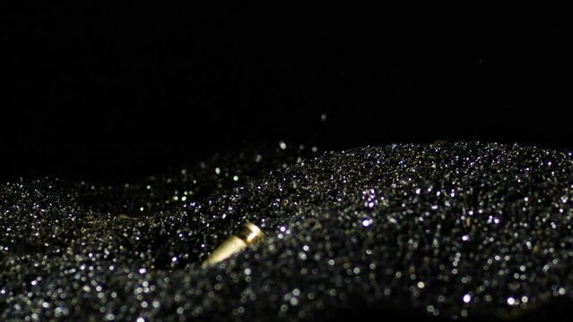 Gun Bullets Falling Into The Black Powder Granules. - closeup shot