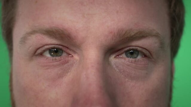 close-up of the eyes of a young red-haired man looking into the frame. on a green background, a close-up of the face of a middle-aged man. tired eyes look into the camera.