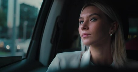 beautiful girl in the car in traffic looks out at the city panorama without thoughts, happy, with the wind in her hair and in a business atmosphere and travel. - Powered by Adobe